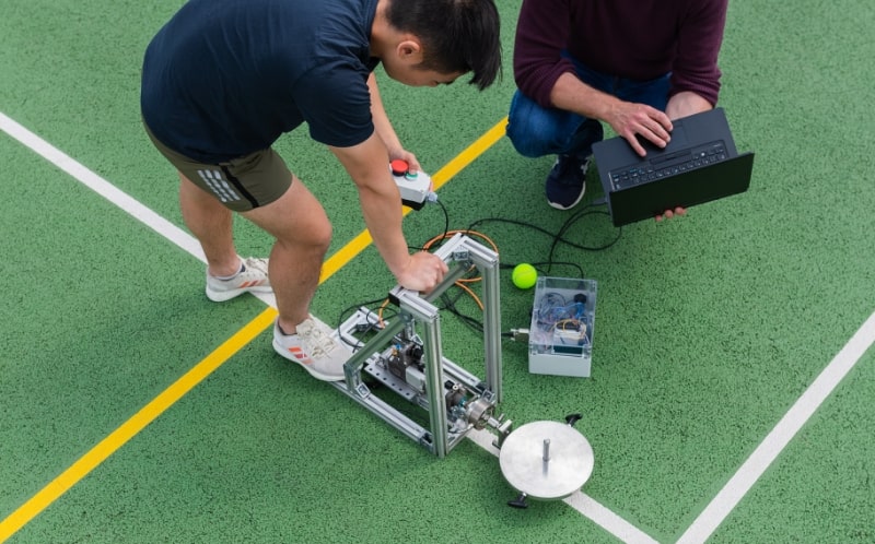 Zwei Personen sind auf einem Sportfeld und arbeiten an einem Experiment